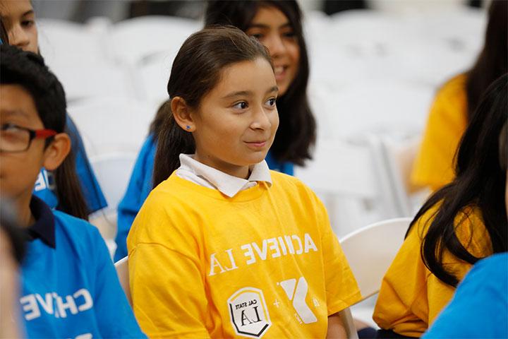 小学生穿着“成就LA”衬衫坐在观众席上